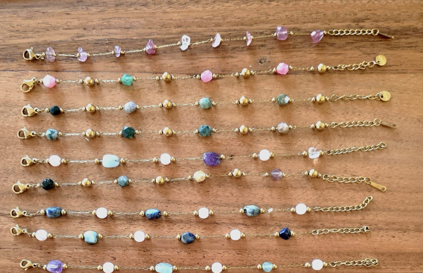 Rows of gemstone bracelets laid out on a wooden board